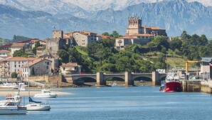 A coastal town with a prominent church on a hill, a bridge, and boats in the harbor.