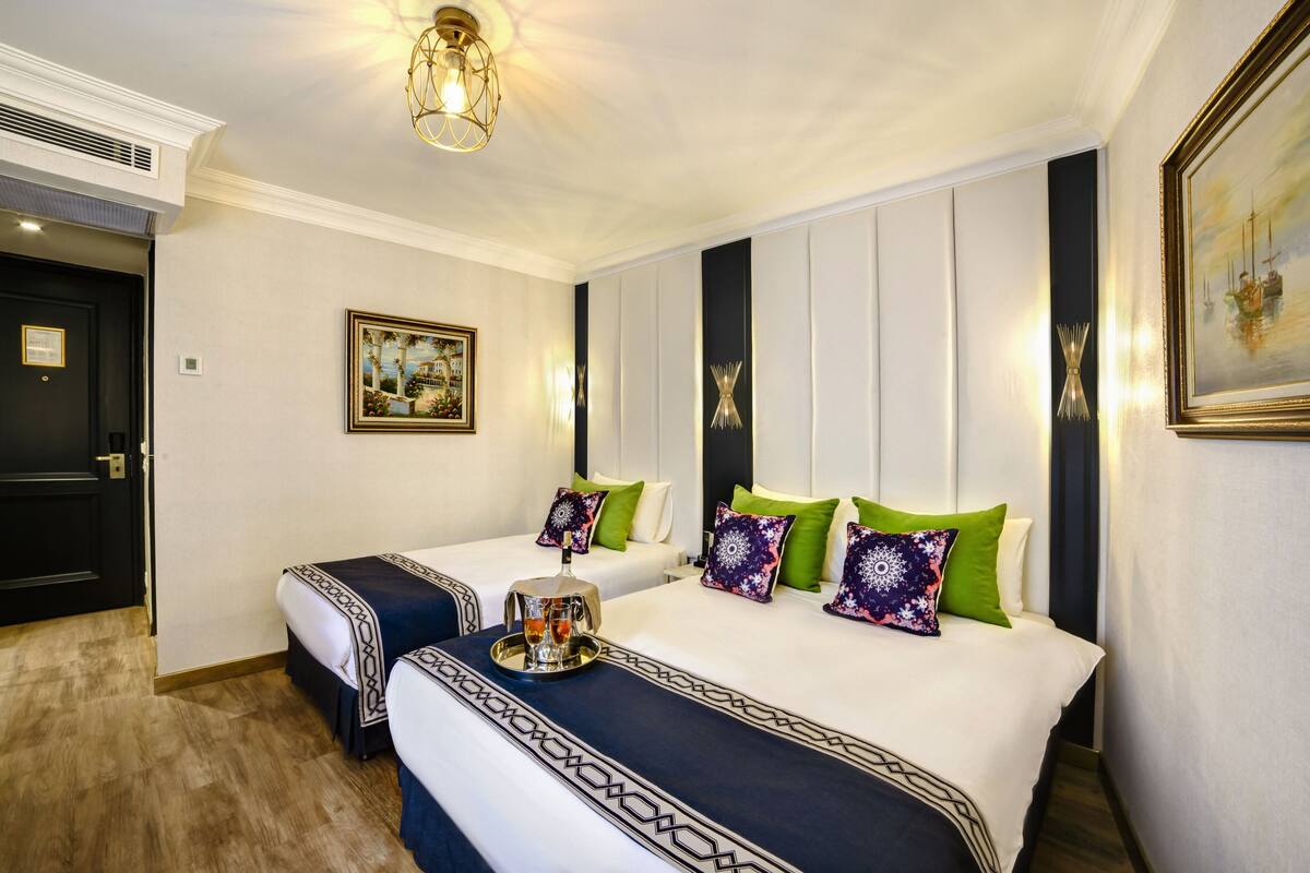 A hotel room with two beds, each with a tray of drinks and decorative pillows.