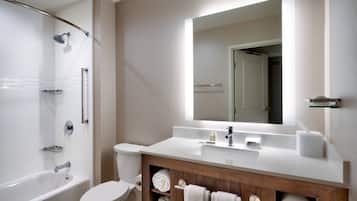 A modern bathroom with a bathtub, toilet, and vanity with a mirror.