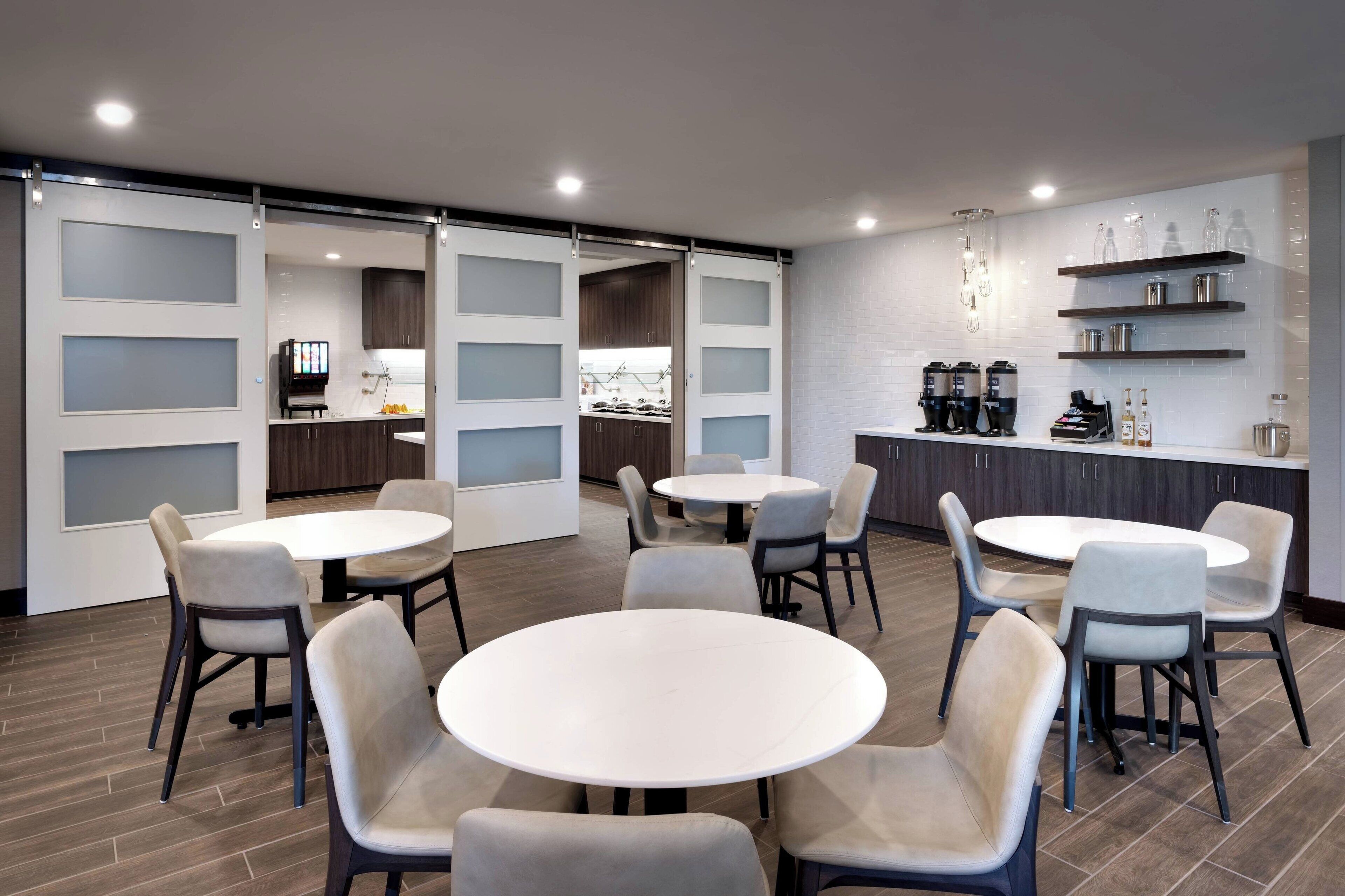 A modern kitchen with white cabinets, a central island, and a coffee station.