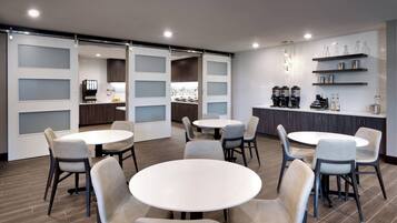 A modern kitchen with white cabinets, a central island, and a coffee station.