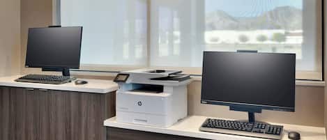 A modern office desk with two monitors, a printer, and a keyboard.