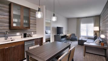 Una habitación de hotel moderna con cocina, una mesa de comedor, un sofá y un televisor.