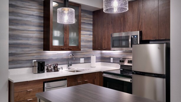 A modern kitchen with stainless steel appliances, wooden cabinets, and a marble backsplash. - Residence Inn by Marriott La Quinta (La Quinta)