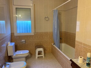 Une salle de bain avec des toilettes, un lavabo et une baignoire.