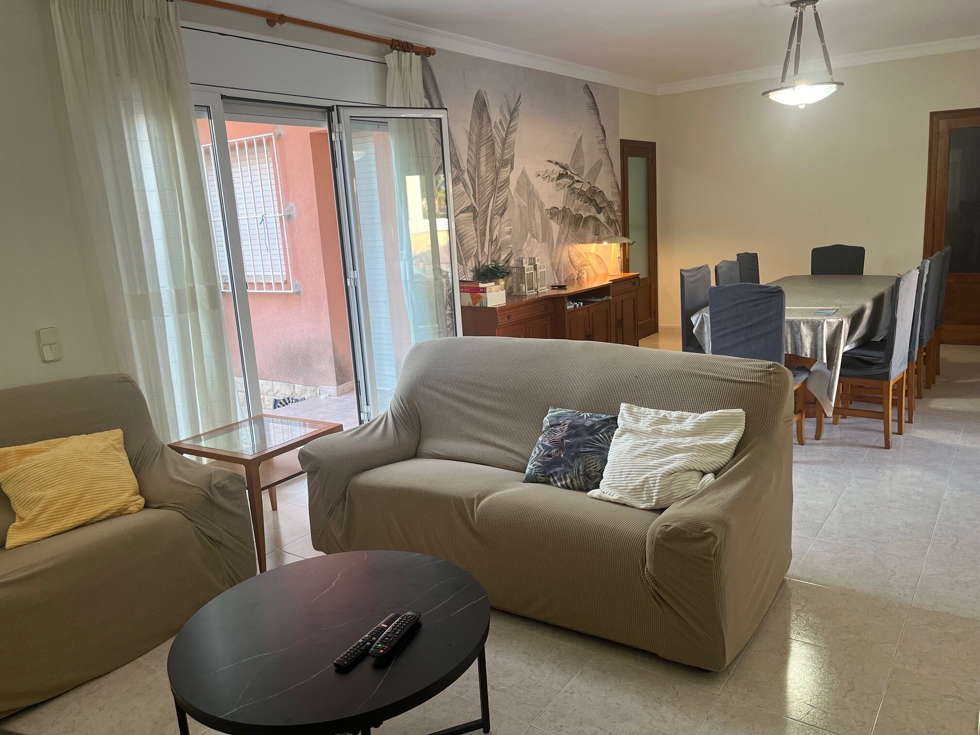 A living room with a sofa, a coffee table, and a dining area with a table and chairs.