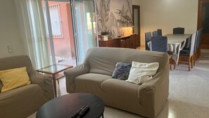 Ein Wohnzimmer mit einer Couch, einem Couchtisch und einem Essbereich mit Tisch und Stühlen.