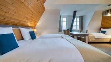 Habitación de hotel con dos camas, techo de madera, una mesa de comedor y una ventana.
