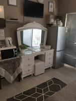 Cozinha compacta com micro-ondas, geladeira e uma bancada pequena.