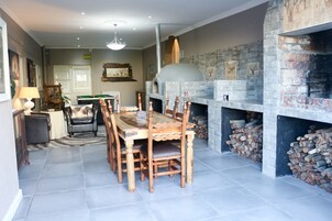 Uma sala de jantar com uma mesa e cadeiras de madeira, uma lareira com revestimento de pedra e um lustre.