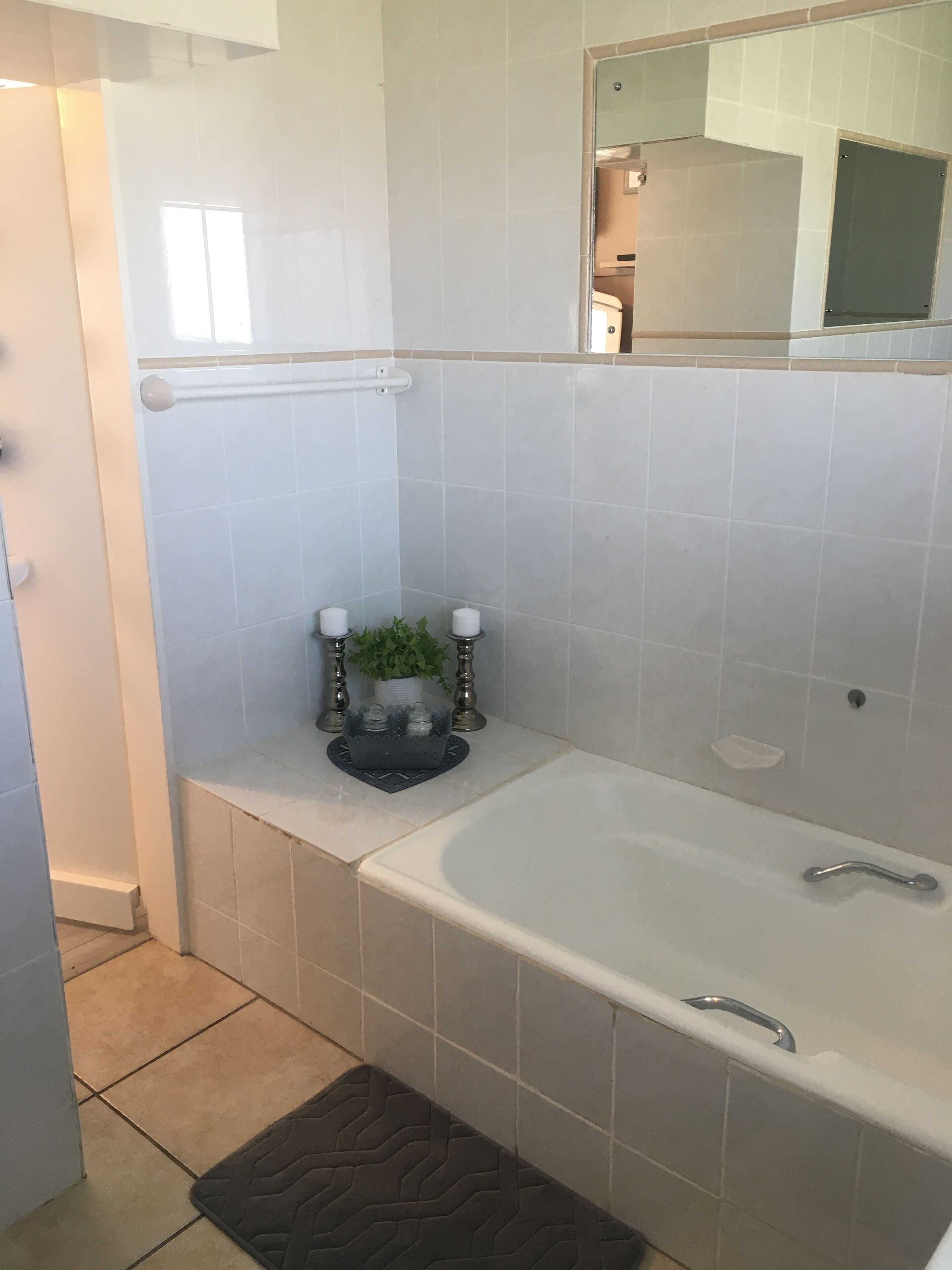 Un baño con bañera, inodoro y lavabo. Hay una planta pequeña en la encimera.
