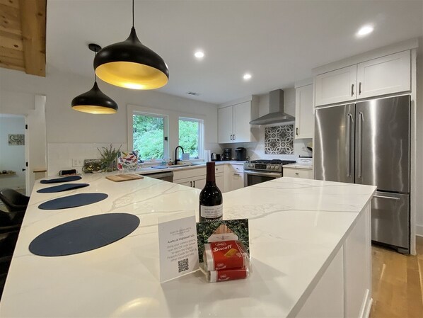 Una cocina moderna con una isla central, electrodomésticos de acero inoxidable e iluminación colgante.
