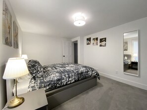 A bedroom with a bed, bedside lamp, and a mirror. - Secluded, Stylish & Completely Reimagined | Azalea at Highlands Falls (Highlands)