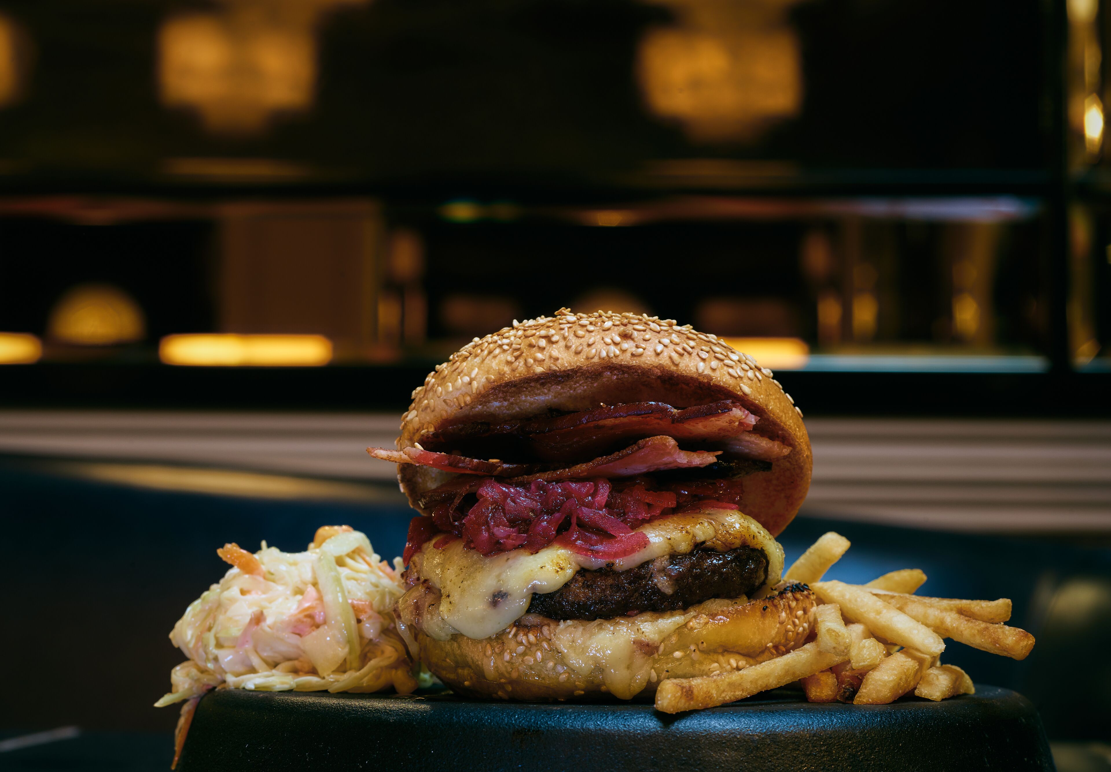 Una hamburguesa con papas fritas sobre un plato negro.
