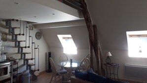 A loft-style living space with a dining area, a staircase, and a kitchen area.