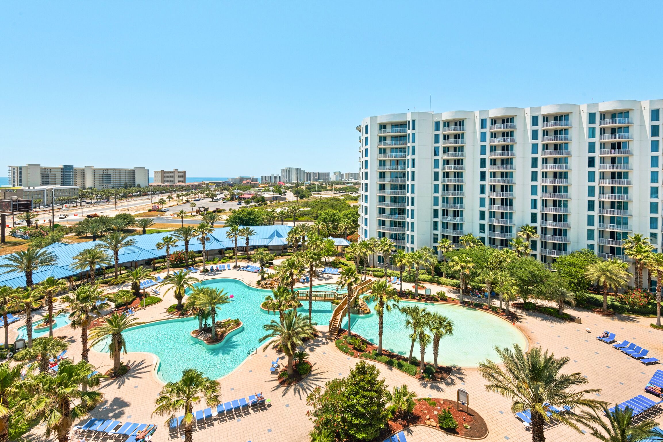A resort with a large pool, palm trees, and a high-rise building.