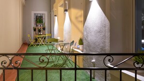 A corridor with a green artificial turf floor, a dining area with chairs and a table, and a staircase with a railing. -  Boutique Hôtel Nice Côte d'Azur (Nice)