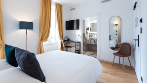 A modern hotel room with a large bed, a desk, a chair, a TV, a mirror, and a bathroom visible through an open door. -  Boutique Hôtel Nice Côte d'Azur (Nice)