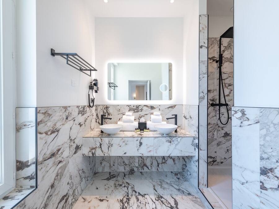 A modern bathroom with a large mirror, two sinks, and a shower area.