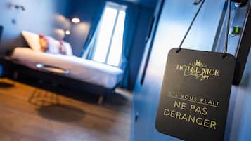 Una habitación de hotel con cama, ventana y un cartel con texto.
