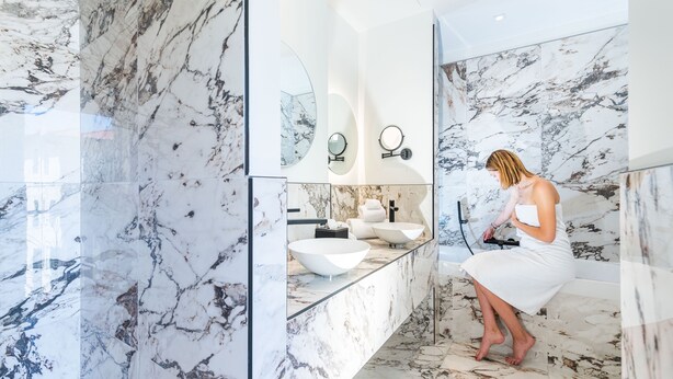 A modern bathroom with a marble floor and walls, a large white sink, and a mirror with two round mirrors above it. -  Boutique Hôtel Nice Côte d'Azur (Nice)