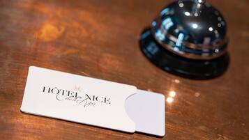 A hotel name card and a bell on a wooden surface.