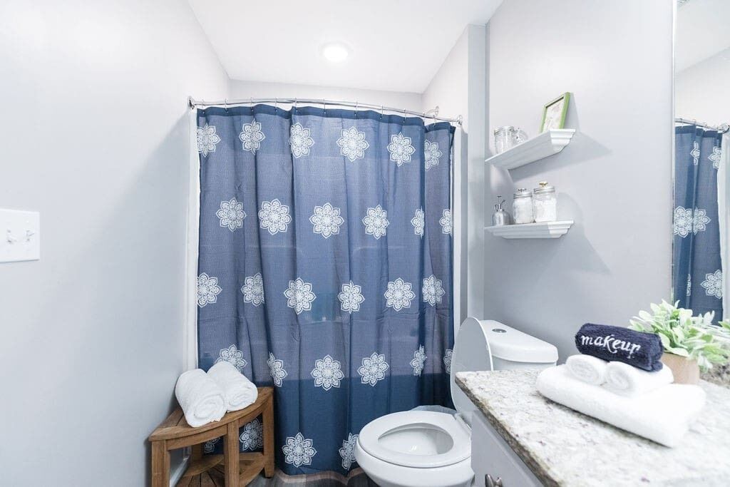 Ein Badezimmer mit Duschvorhang, Toilette, Waschbecken und Ablage für Toilettenartikel.