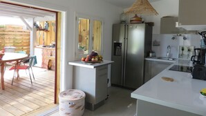 A compact kitchen with a refrigerator, a sink, and a dining area with chairs and a table. - Vacation home with heated pool (La Teste-de-Buch)