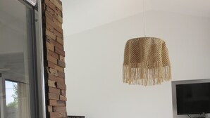 A modern bedroom with a brick accent wall, a large bed, a television, and a hanging light fixture. - Vacation home with heated pool (La Teste-de-Buch)