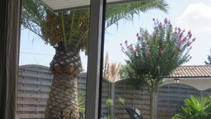A poolside area with a lounge chair, a palm tree, and a wooden deck. - Vacation home with heated pool (La Teste-de-Buch)