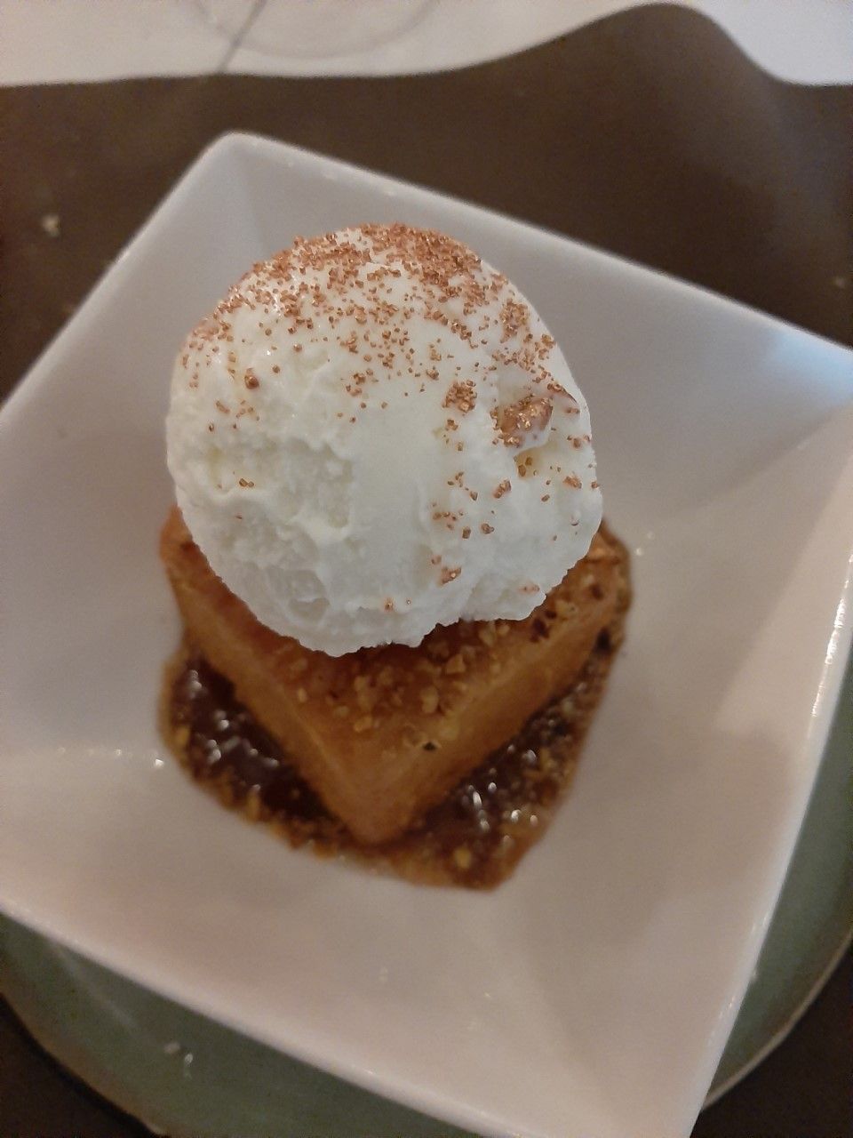 Un dessert surmonté d’une boule de glace, servi dans une assiette carrée.