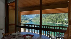 A dining area with a table set for two, overlooking a lake and forested mountains.