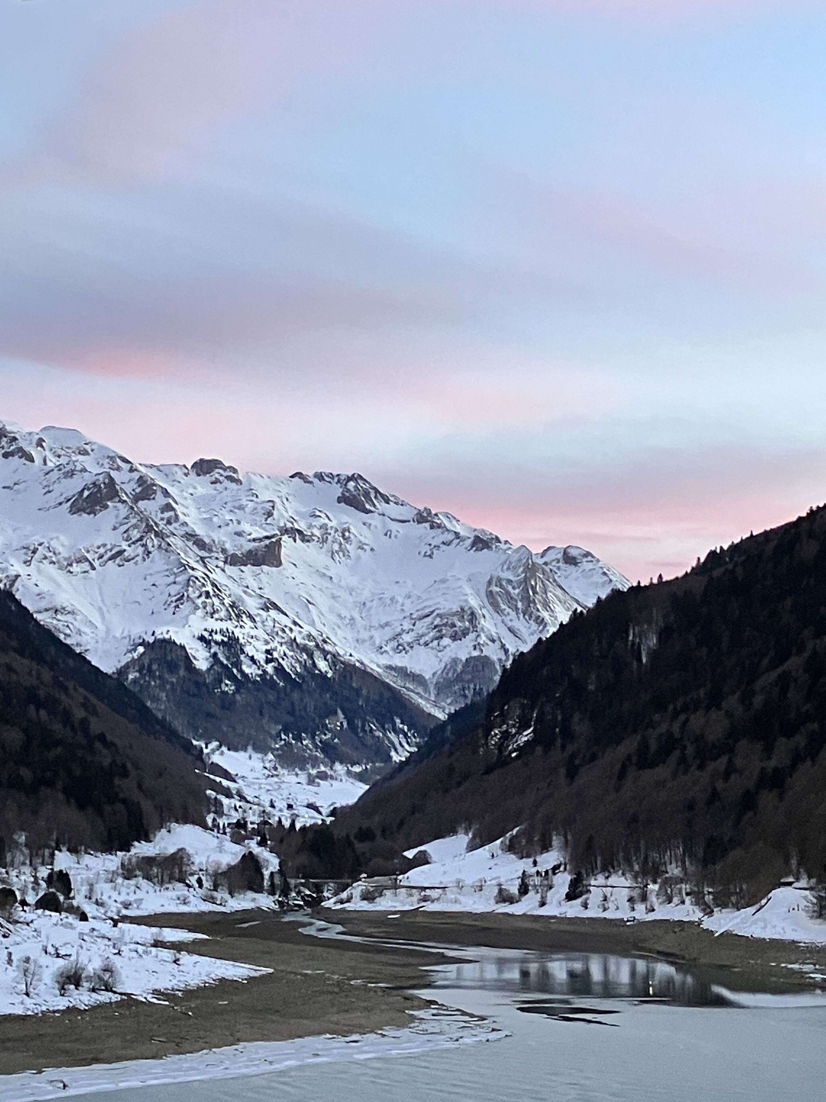 A mountainous landscape with snow-covered peaks and a river flowing through a valley.