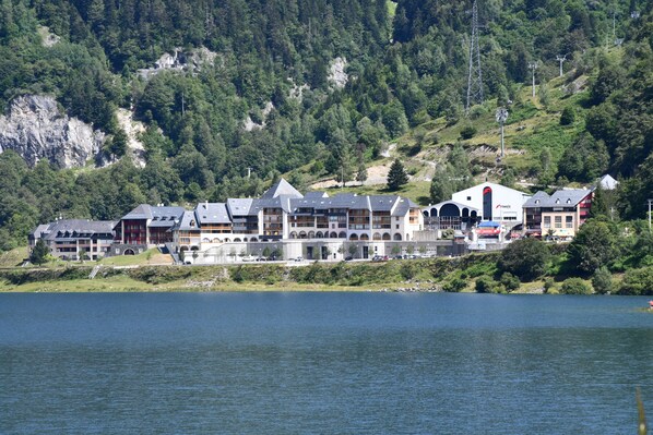A lakeside hotel with multiple buildings, including a prominent red building and several with grey roofs.