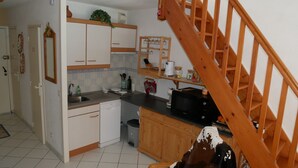 A compact kitchen with wooden cabinets, a microwave, and a wooden staircase. - 5-bed apartment with superb view of Lake Artouste (Laruns)