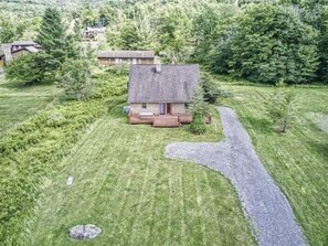 A house with a stone roof, surrounded by a well-maintained lawn and a gravel path leading to the entrance. - YR10- AC! Pet Friendly! Hot tub! (Davis)