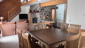 A dining area with a wooden table and chairs, a stone wall, and a staircase. - YR10- AC! Pet Friendly! Hot tub! (Davis)