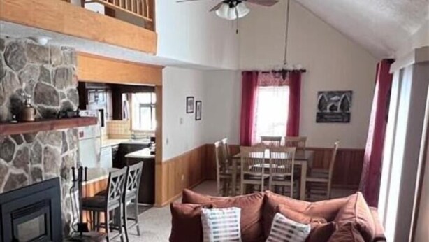 A cozy living room with a stone fireplace, a brown sofa, a coffee table, and a dining area with a wooden table and chairs. - YR10- AC! Pet Friendly! Hot tub! (Davis)