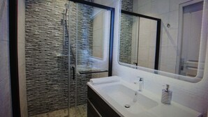 A bathroom with a large mirror, a sink, and a shower area.