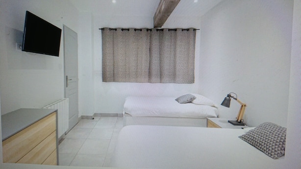 A bedroom with a bed, a desk, a chair, a lamp, and a window with curtains.