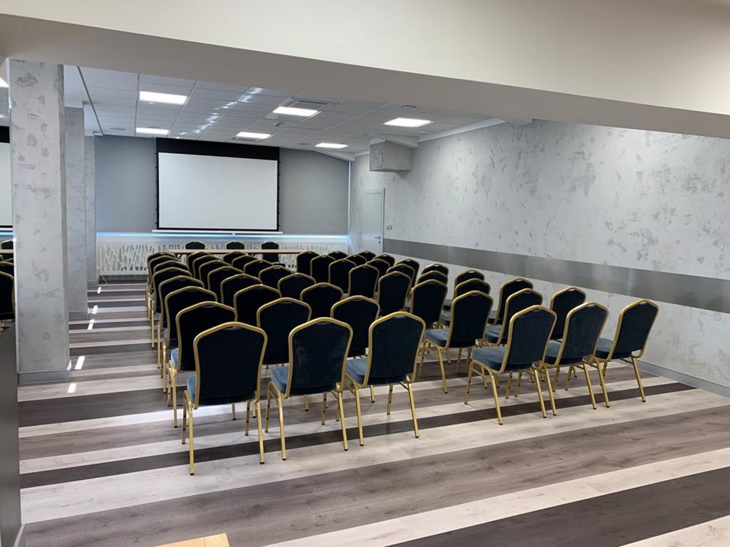 A conference room with rows of chairs, a projector screen, and a whiteboard.