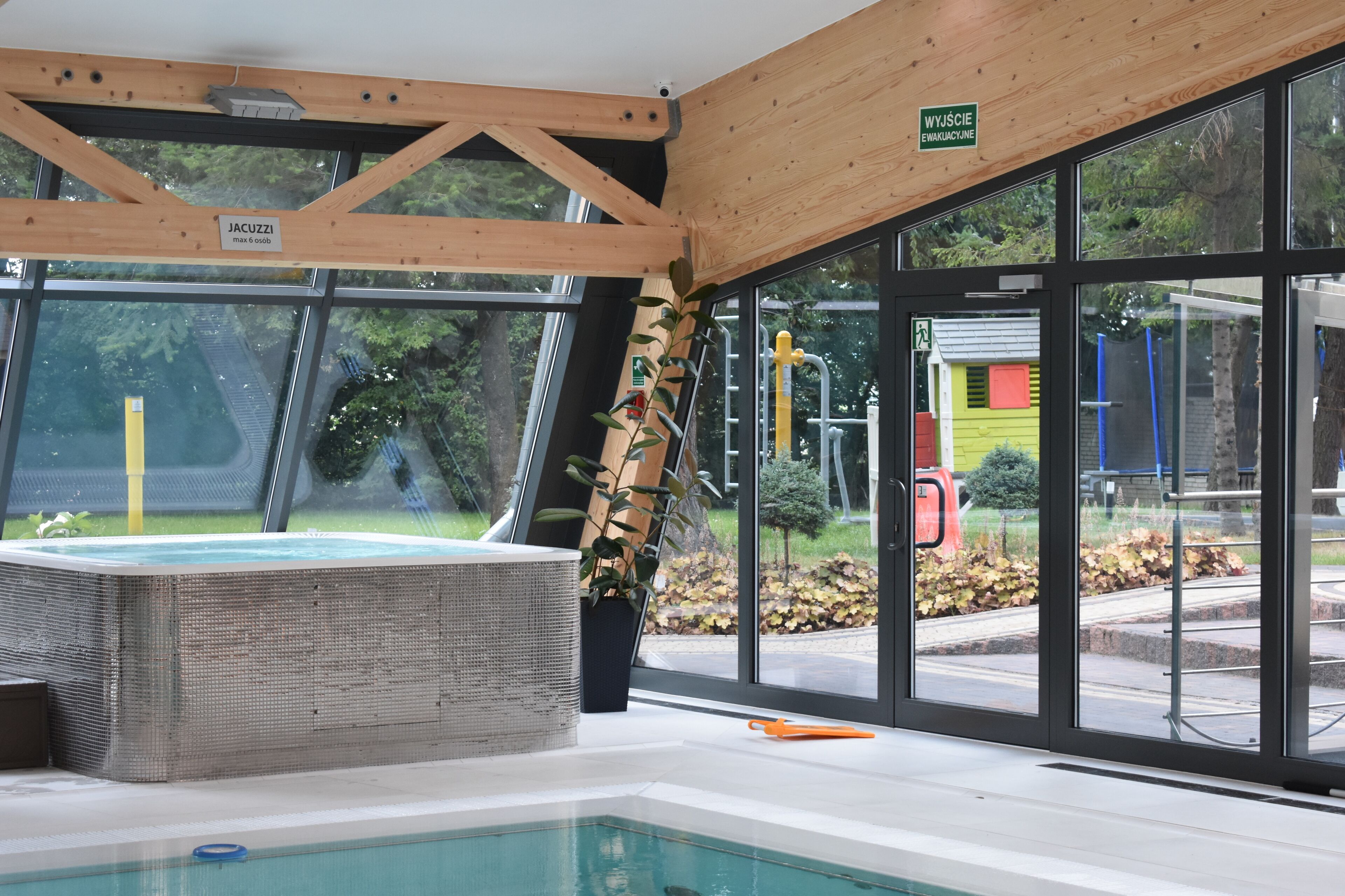 A hot tub area with a view of the outside, including a sign for 'JACUZZI' and a wooden ceiling structure.