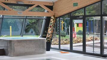 A hot tub area with a view of the outside, including a sign for 'JACUZZI' and a wooden ceiling structure.