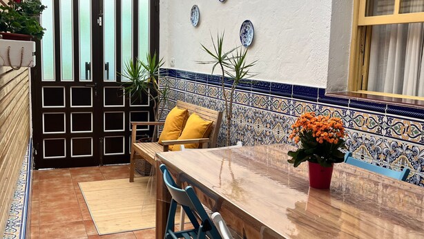 A patio with a wooden table and chairs, a tiled floor, a door with glass panels, and decorative plates on the wall. - Holiday Home Casa del Molino with Sea & Mountain Views, Wi-Fi, and Terrace (Icod de los Vinos)