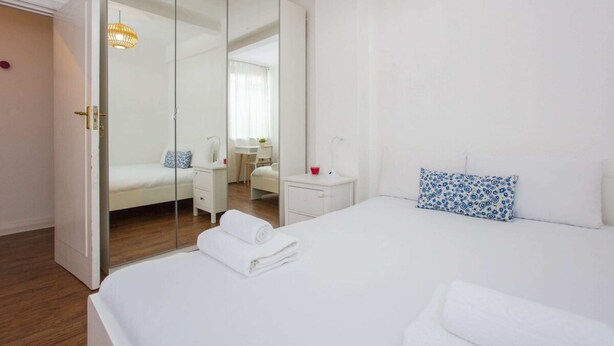 Una camera d'albergo moderna con un letto grande, un comodino, uno specchio e un armadio.