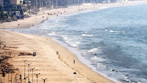 A beach with a sandy shore, a few people, and buildings in the background. - Hotel Gateway Inn (Mumbai)