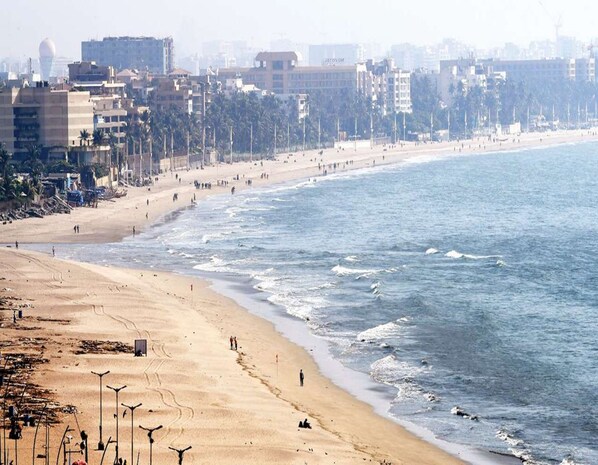 A beach with a sandy shore, a few people, and buildings in the background.