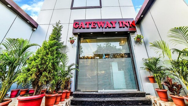 A modern building with a "GATEWAY INN" sign, featuring a large glass entrance and potted plants around the entrance. - Hotel Gateway Inn (Mumbai)