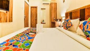 A hotel room with a bed, a wooden headboard, and a colorful mosaic floor. - Hotel Gateway Inn (Mumbai)