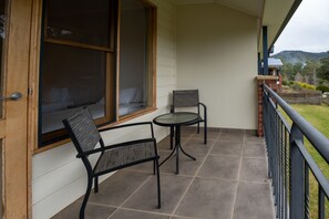 Een balkon met een bed, twee stoelen en een tafel.